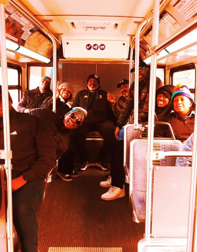 A group of people sitting and standing inside a city bus.